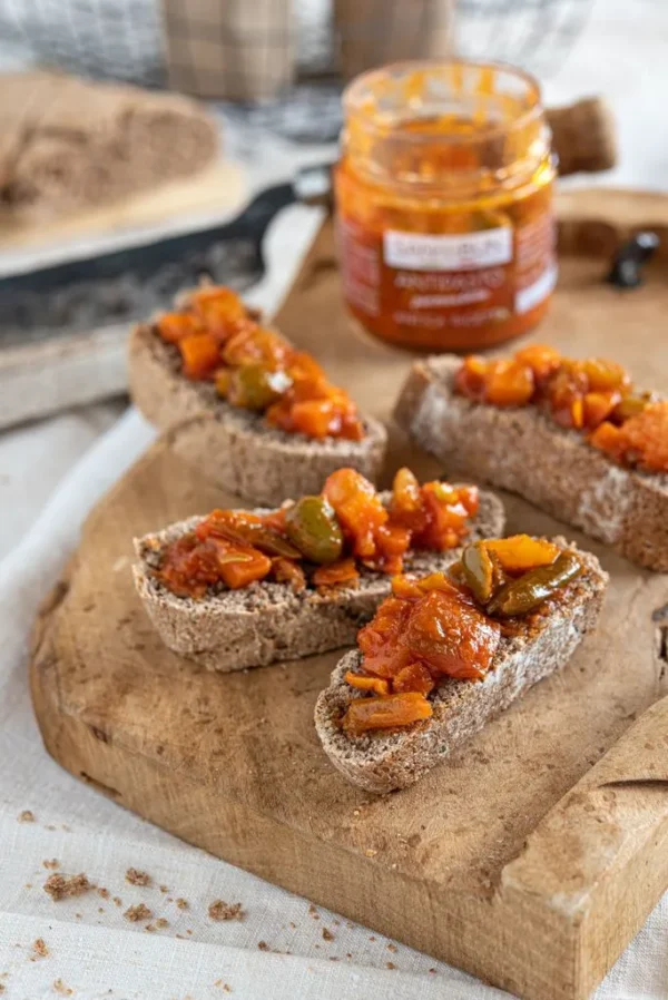 Antipasto piemonckie na czterech kromkach chleba. W tle słoik z pastą.