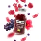 Organiczny napar z hibiskusa, truskawek i winogron w szklanej butelce. W tle winogrona i hibiskus