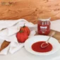 Na stole passata pomidorowa w talerzu i obok w szklanym słoiku. Obok talerza dwa pomidory w białym ręczniku.